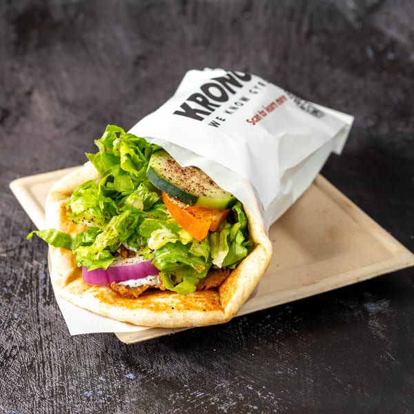 A Kronos Gyro, filled with meat, lettuce, red onion, cucumber, and tomato, on a tray.